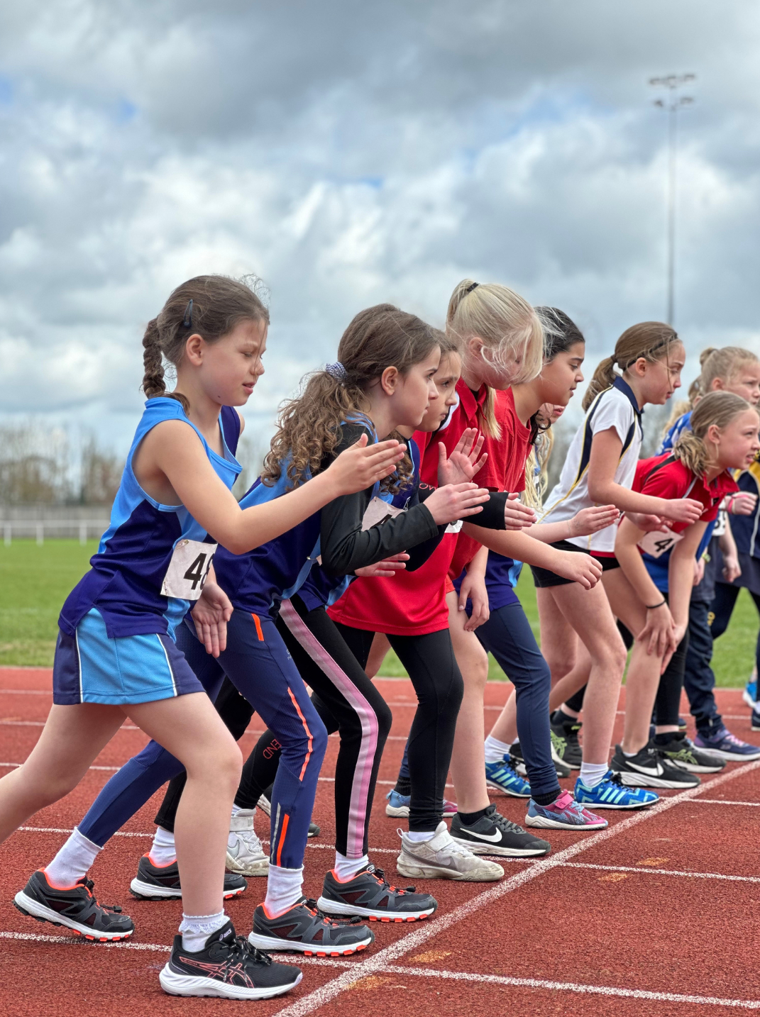 Primary School aged girls ready to start a running race at an athletics track